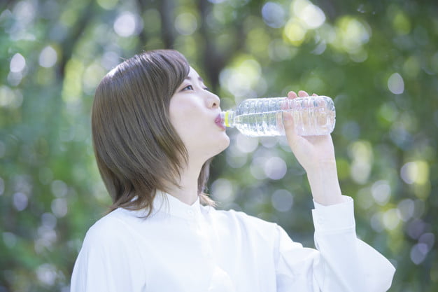 Seorang wanita sedang minum air mineral
